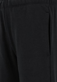 Zwarte katoenen joggingbroek met een elastische tailleband en zijzakken. De stof heeft een gladde, zachte textuur zonder zichtbare patronen.