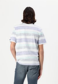Stripet T-shirt i lyseblå, grå og hvide farver. Korte ærmer, rund hals og blødt, let materiale. Bæres med blå jeans.