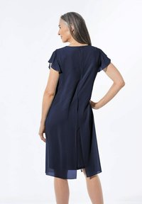 Navyblaues Kleid mit kurzen, flatternden Ärmeln, Reißverschluss im Rücken und einem hohen Schlitz bis zum Oberschenkel, aus leichtem Stoff mit glatter Textur.
