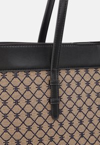 Sac cabas avec poignées et bordure en cuir noir, en tissu beige avec un motif géométrique bleu marine.