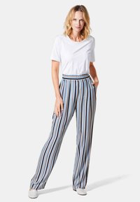 Gestreepte wijde broek in blauw, wit en oranje. Voorzien van een elastische tailleband en zijzakken. Gepaard met een plain wit T-shirt.