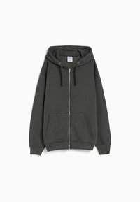 Sudadera con cremallera de color gris oscuro, hecha de una tela suave, con una gran capucha, bolsillos delanteros, puños acanalados y un corte relajado.