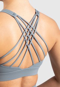 Szary stanik sportowy z wieloma skrzyżowanymi ramiączkami z tyłu, wykonany z elastycznego materiału, o gładkiej fakturze i szerokiej taśmie.