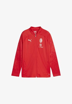 Giacca da calcio in poliestere rossa con zip integrale, maniche con motivo, logo Puma e stemma del club. Presenta due tasche laterali e un colletto alla coreana.
