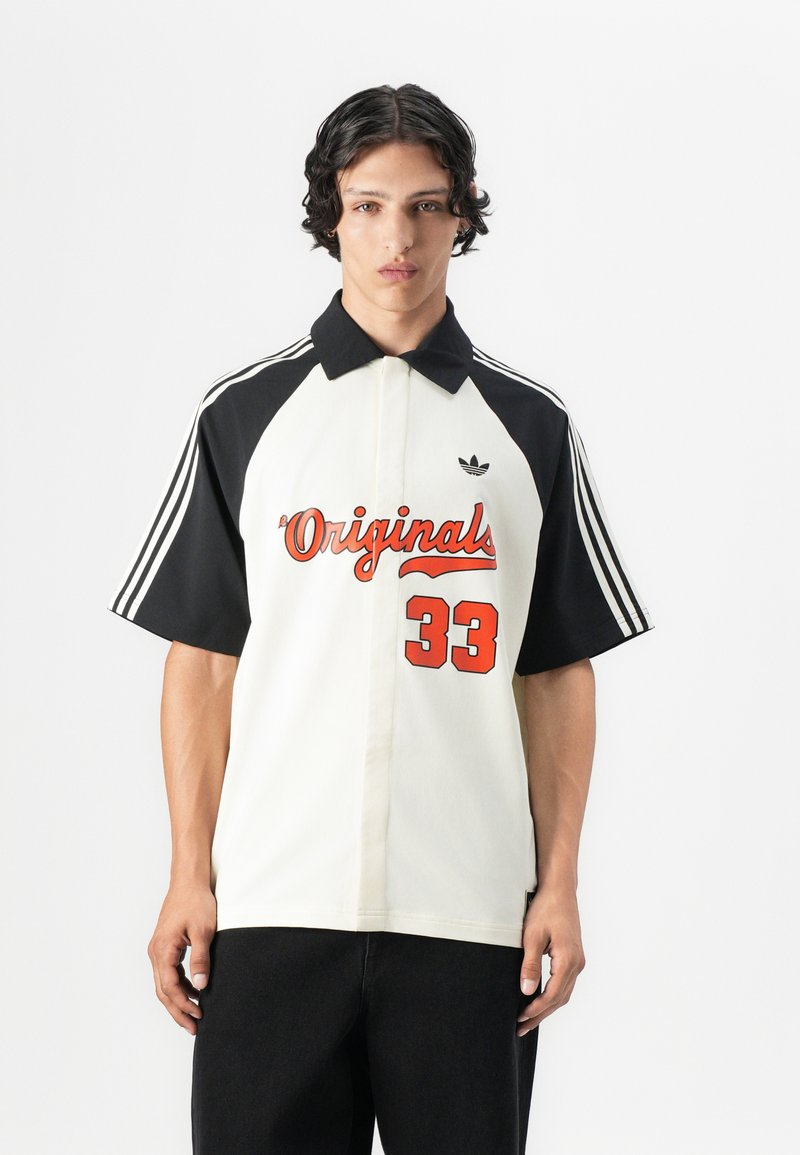 Short-sleeve polo shirt featuring a white body with black sleeves, red "Originals" text, and the number "33," made from a lightweight fabric.