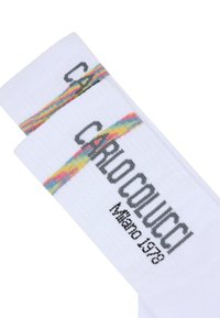 Hvite bomullssokker med en fargerik vandret stripe og teksten "CARLO COLUCCI Milano 1978" i sort. Bløt tekstur, standard sokkeform.