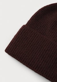 Burgundy knitted beanie with a ribbed texture. Soft material, tapered shape with a folded cuff.