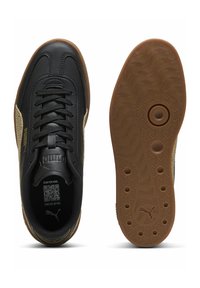 Tomaia sintetica nera con accenti dorati, design con lacci e suola in gomma color sabbia con motivo ondulato e dettagli circolari.