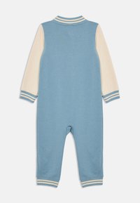 Blauer und cremefarbener Baumwoll-Overalls für Kleinkinder mit langen Ärmeln, gestreiften Bündchen und einem gerippten Kragen. Glatte Textur mit lockerer Passform.