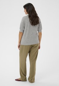 Harmaa teksturoitu lyhythihainen paita, jossa on käärityt hihansuut, yhdistetty löysiin oliivinvihreisiin housuihin, joita täydentävät viininpunaiset ballerinat. Yksinkertainen, rento malli.