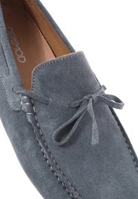 Grijze suède loafers met een decoratieve strik, gestikte details en een gladleren binnenkant. De zool is plat voor draaggemak.