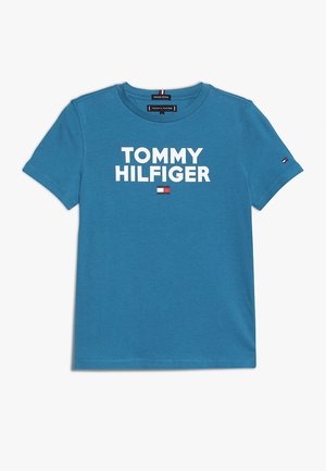 T-shirt bleu en coton à manches courtes avec le texte "TOMMY HILFIGER" et un petit logo rouge, blanc et bleu marine centré en dessous et sur la manche gauche.
