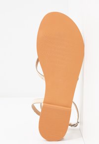 Světlé béžové sandály s hladkou, texturovanou gumovou podrážkou, s béžovými popruhy a jednoduchým designem s přezkou. Elegantní a minimalistický styl.
