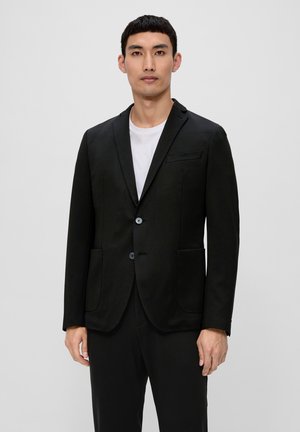 Schwarzer Blazer aus glattem Stoff, mit Reverskragen, zwei Knöpfen und seitlichen Taschen. Das Model trägt ein weißes T-Shirt darunter.