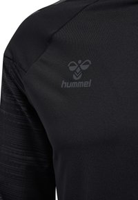 Maglietta sportiva nera con un design testurizzato sulla manica sinistra, caratterizzata da un logo grigio sottile di "hummel" nella parte alta del torace.