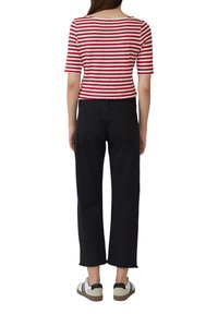 Top a righe rosse e bianche con maniche corte abbinato a jeans neri a vita alta, con orlo grezzo e sneakers casual.