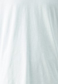 Camiseta de algodón azul claro con una tela suave y ligeramente texturizada. Diseño simple que presenta un cuello redondo y mangas cortas.