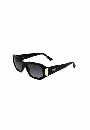 Occhiali da sole rettangolari neri oversize con lenti sfumate e logo dorato "GUESS" sull'asta.