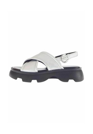Sandal in pelle argentata con cinturini incrociati, fibbia regolabile alla caviglia e suola in gomma nera chunky. Presenta una texture liscia e un design contemporaneo.