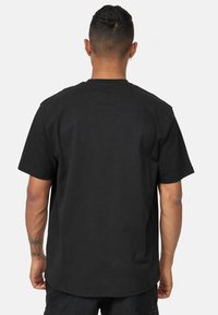 Svart bomullströja med avslappnad passform, korta ärmar och klassisk rund halsringning. Inga synliga tryck eller mönster.