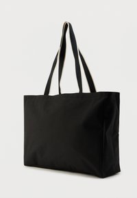 Μαύρη τσάντα tote από καμβά με διπλά κοντά λουριά και αντίθετη ανοιχτόχρωμη λεπτομέρεια στα περιθώρια. Ορθογώνιο σχήμα και μαλακή υφή.