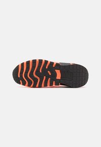 Sort atletisk sko sål med orange zigzag-mønster. Har dybe dæksler for greb og struktureret gummimateriale. Flad, bred design.
