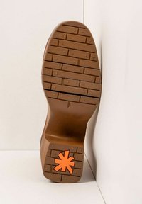 Suela de goma marrón con un patrón de agarre texturizado, que presenta un destacado diseño de estrella naranja en el centro.