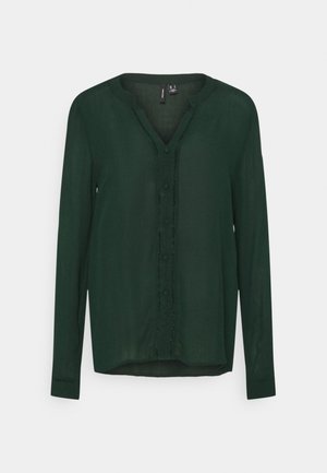 Donkergroene blouse met lange mouwen, ronde hals, knoopsluiting aan de voorkant en subtiele getextureerde bies langs de sluiting.