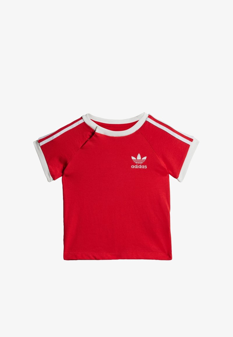 Červené bavlnené tričko s krátkymi rukávmi, bielym okrúhlym výstrihom a tromi pruhmi na každom pleci. Obsahuje vyšitý logotyp adidas na hrudi.