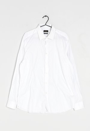 Valkoinen pitkähihaisista nappikauluspaita, jossa on kärkipäät, valmistettu sileästä kankaasta, suoran leikkauksen ja pehmeiden ryppyjen kanssa.