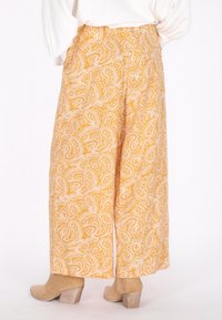 Gele paisley patroon wijde broek van lichtgewicht stof, voorzien van een hoge taille en ruime silhouet. Gecombineerd met beige haklaarzen.