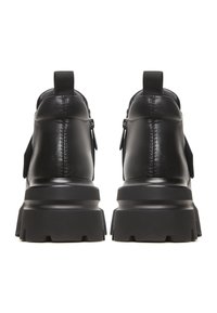 Botines negros de cuero con suelas gruesas y texturizadas, con cremalleras laterales y tiradores traseros para facilitar su uso. Acabado liso.