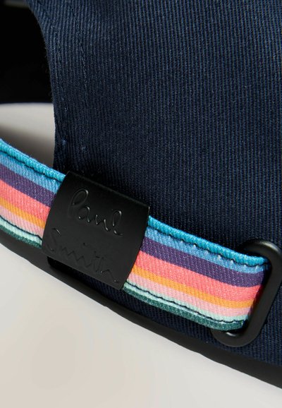 Sangle en tissu bleu marine réglable avec boucle noire et bande tissée aux couleurs de l'arc-en-ciel, ornée du logo "Paul Smith" en relief.