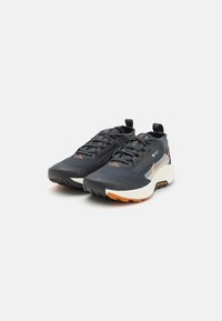 Trail-løbesko med en overdel i sort mesh, orange detaljer, struktureret gummisål og en polstret mellemsål, der er designet til stabilitet og greb.