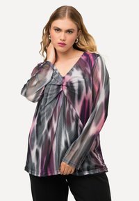 Pitkähihaista paitoa, jossa on läpikuultavaa kangasta, koristelee monivärinen abstrakti kuvio, joka sisältää pinkkiä, purppuraa ja mustaa. V-neck-muotoilu, jossa on kerättyjä yksityiskohtia.