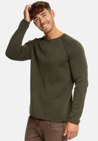 Chemise à manches longues en vert olive texturé avec des côtes horizontales et un col rond. Présente un design ajusté et des détails de couture subtils.