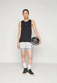 Musta hihaton paita, jossa on pieni logo, vaaleanharmaat shortsit, joissa on sinisiä yksityiskohtia, mustat lenkkarit ja kädessä musta koripallo vaaleanpunaisilla yksityiskohdilla.