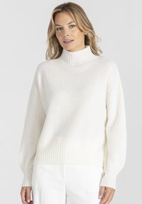 Sweter w kolorze kremowym z wysokim prążkowanym kołnierzem, luźnymi rękawami i prążkowanym dołem. Teksturowany dzianinowy materiał zapewnia miękki wygląd i uczucie.