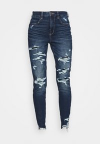 Mörkblå denimjeans med smal passform, som har slitna detaljer, hål och fransade fållar för ett slitet utseende. Hög midja.