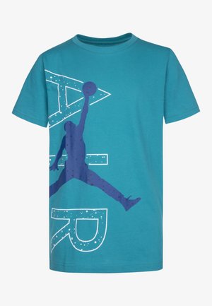 Camiseta de manga corta turquesa con una gran silueta azul marino de un jugador de baloncesto saltando y sosteniendo un balón, sobre letras delineadas en blanco.