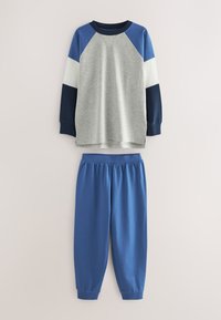 Grå sweatshirt med lange ærmer med blå, hvide og marineblå ærmer kombineret med ensfarvede blå joggingbukser med elastisk talje.