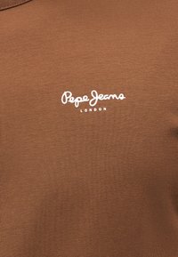 Tissu marron avec le logo blanc "Pepe Jeans London" imprimé au centre.