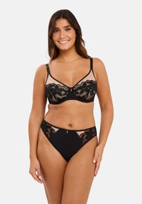 Soutien-gorge en dentelle noire avec culotte assortie. Le soutien-gorge présente un superposition en dentelle florale, des panneaux transparents et des bretelles réglables. La culotte comporte des accents en dentelle.