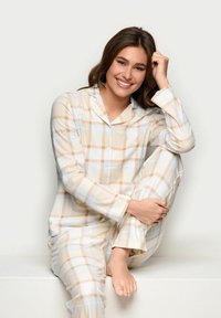 Beige und hellblau karierter Schlafanzug aus weichem Stoff. Enthält ein knöpfbares Oberteil und passende Hose, mit lockerer Passform und langen Ärmeln.