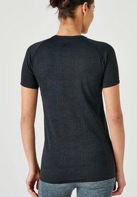 Camiseta atlética negra de manga corta con un patrón geométrico texturizado en la parte posterior y un logo en el cuello.