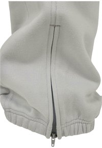 Hellgraue Zip-Hoodie mit geripptem Bund, einem metallischen Reißverschluss und weicher Textur mit dezenten Nähdetails.