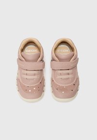 Baskets en cuir rose avec une sangle en velcro, des accents texturés et des motifs d'étoiles sur les côtés. Semelle en caoutchouc avec de petites rainures circulaires.