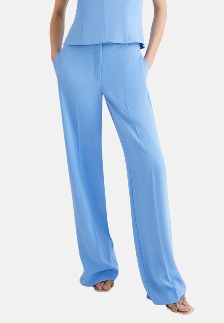Pantaloni larghi blu chiaro realizzati in tessuto morbido, con tasche laterali e una vestibilità comoda, abbinati a una blusa coordinata.
