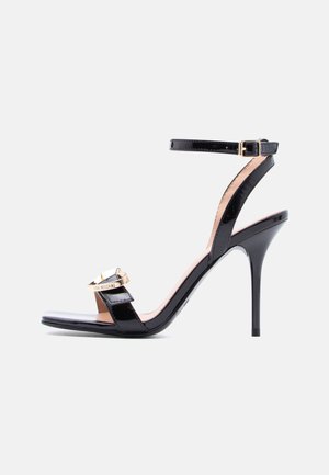 Black patent leather stiletto sandal with ankle strap and gold-tone buckle featuring "Love Moschino" logo, set against a plain background.