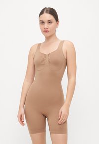 Formverbessernder Bodysuit in Beige, mit einem taillierten Design, gerafftem Mittelteil, breiten Trägern und einer Länge bis zur Mitte des Oberschenkels. Glattes, dehnbares Material.